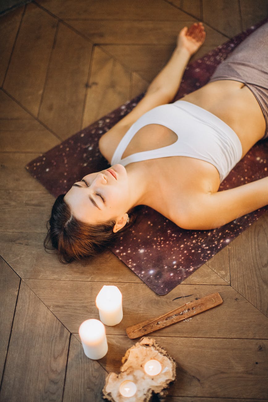 Femme allongée sur un tapis de yoga avec des bougies et de l'encens
